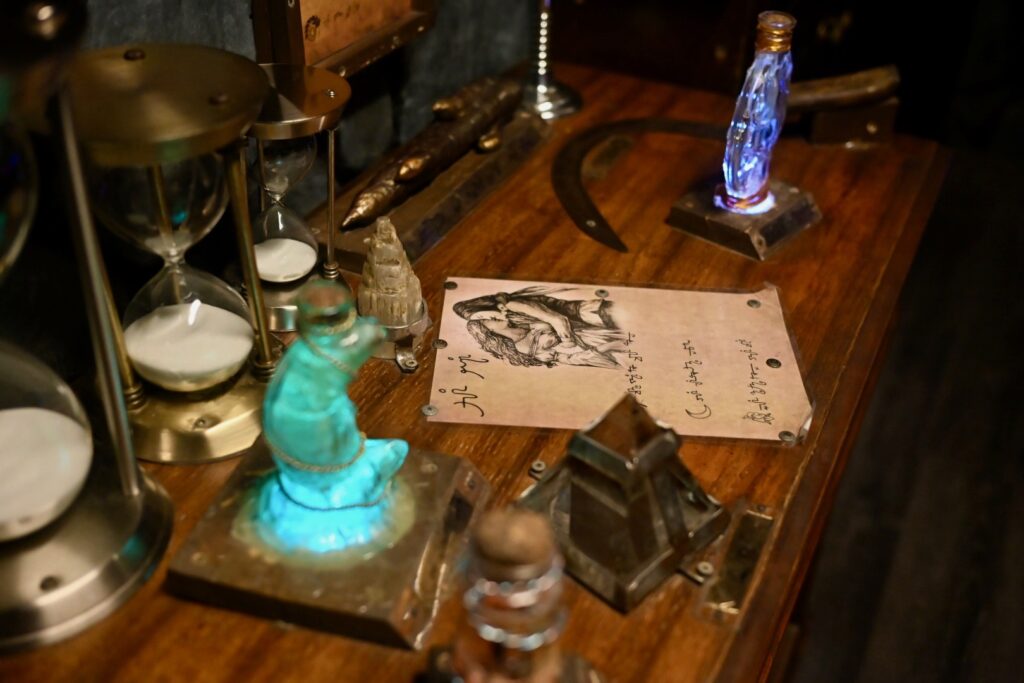 A desk covered with glowing potion bottles, magical tools, and a recipe in a made-up language.