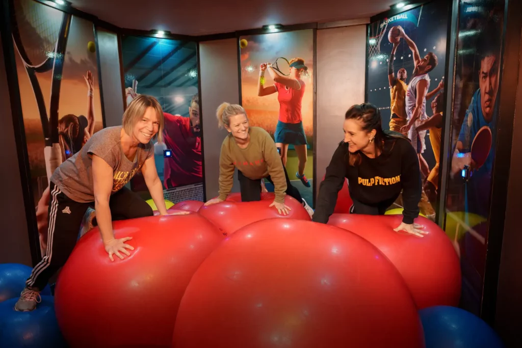 tre glada kvinnor klättrar på stora röda pilatesbollar