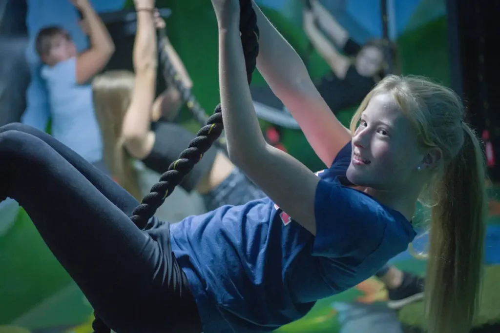 glad tjej med långt hår svingar sig i en lian