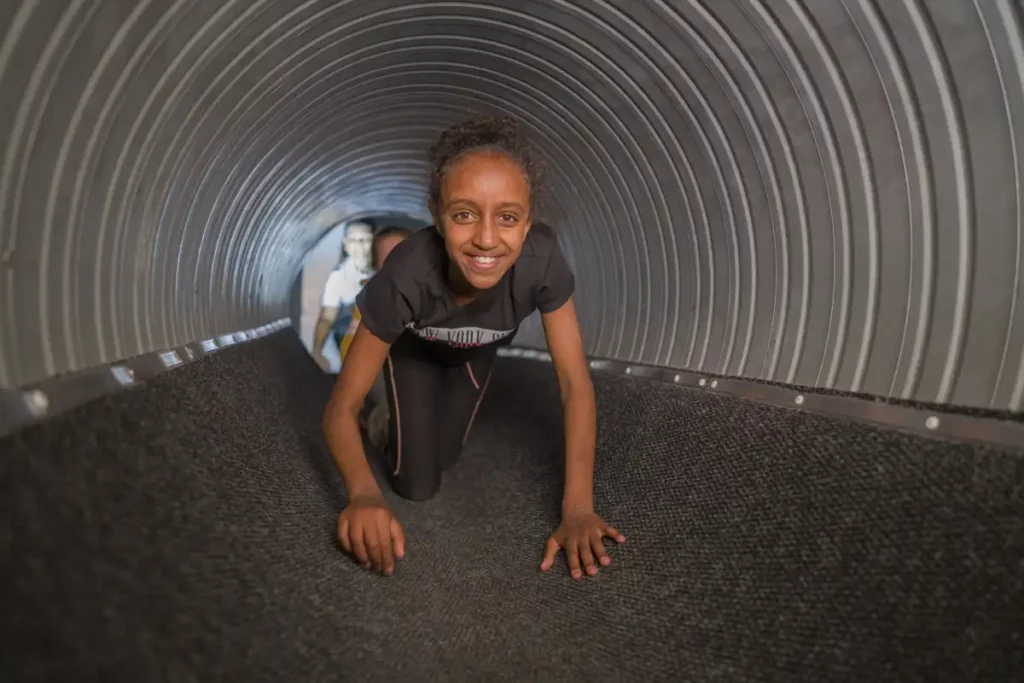 En glad tjej kryper genom ett rör
